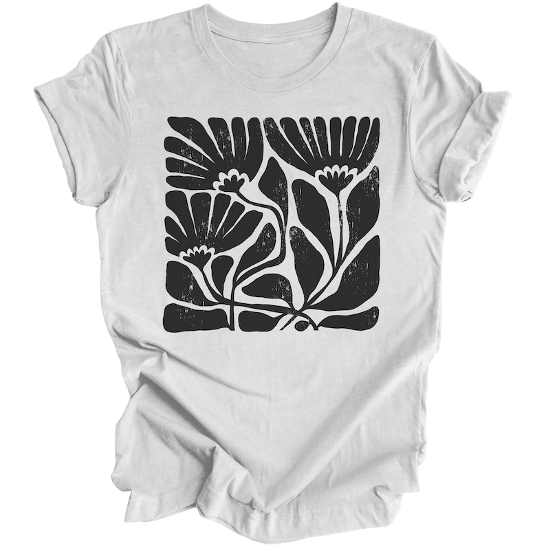 May include: White t-shirt with a black floral print design. The design features stylized flowers and leaves in a square shape.