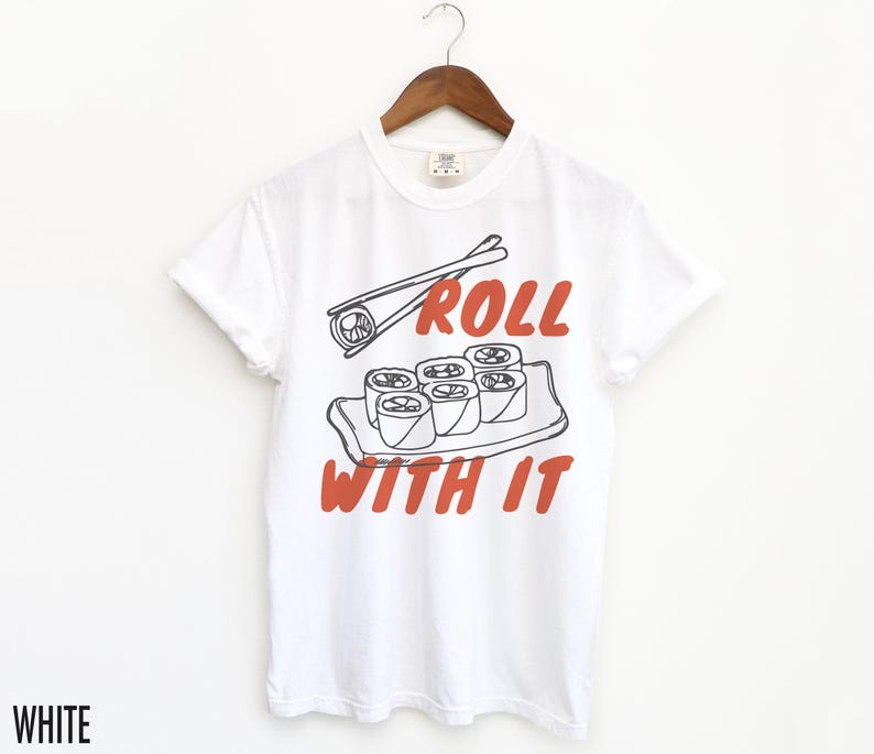May include: White t-shirt featuring a graphic of sushi rolls and chopsticks. The text "Roll with it" is printed in red on the shirt.