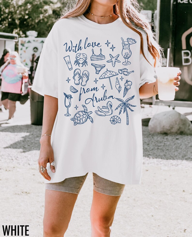Puede incluir: Camiseta blanca con ilustraciones y texto en azul. El dise&ntilde;o incluye un cangrejo, un traje de ba&ntilde;o, una estrella de mar, gafas de sol, un helado y las palabras "With love from Aruba". La camiseta es holgada.