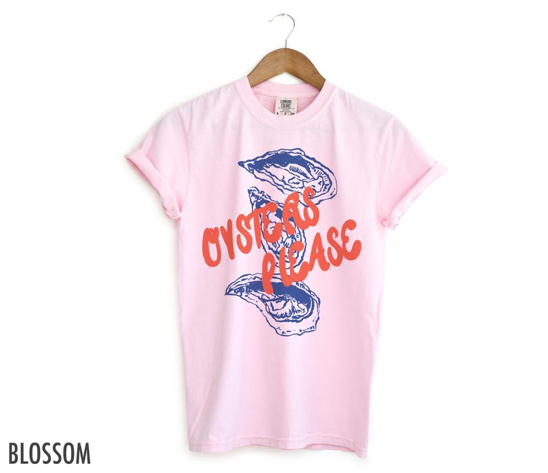 May include: Pink t-shirt with a blue and white illustration of oysters and the text "Oysters Please" in red.