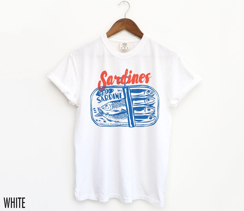 K&ouml;nnte beinhalten: Wei&szlig;es T-Shirt mit einer blauen und roten Grafik einer Sardinenb&uuml;chse. Der Text auf der Dose lautet "Sardine" und "Sardines".