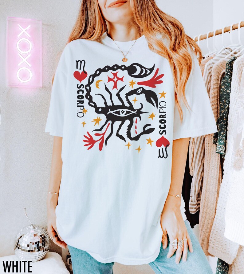 K&ouml;nnte beinhalten: Wei&szlig;es T-Shirt mit einem Grafikdruck eines Skorpions mit einem roten Herzen und dem Wort "Scorpio", das vertikal auf beiden Seiten des Skorpions geschrieben ist.