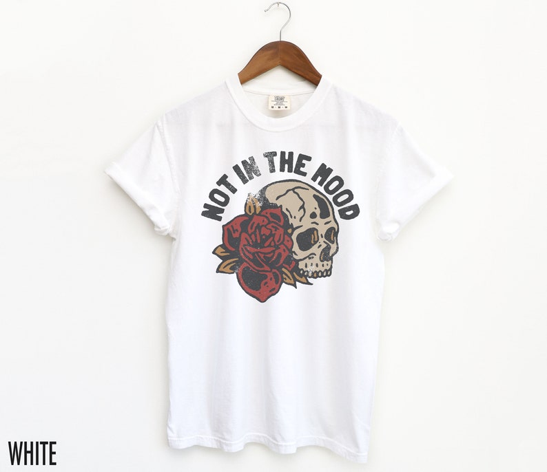 May include: White t-shirt with a skull and rose graphic and the text "Not in the Mood".