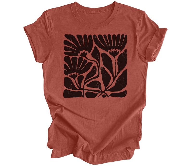 May include: A rust-colored t-shirt with a black floral print. The print is a stylized design of flowers and leaves.