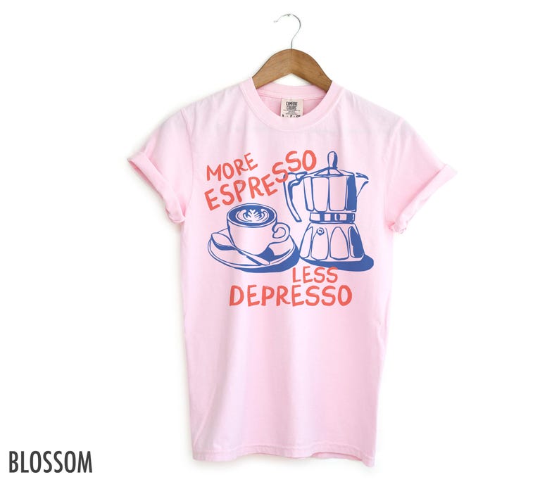 May include: Pink t-shirt with a blue and white illustration of a coffee pot and a cup of coffee. The text on the shirt reads "More Espresso Less Depresso".