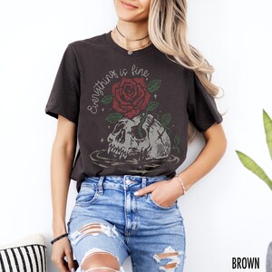 K&ouml;nnte beinhalten: Ein schwarzes T-Shirt mit einem Aufdruck eines Sch&auml;dels, aus dem eine rote Rose w&auml;chst. Der Text "Everything is fine" steht &uuml;ber dem Sch&auml;del.