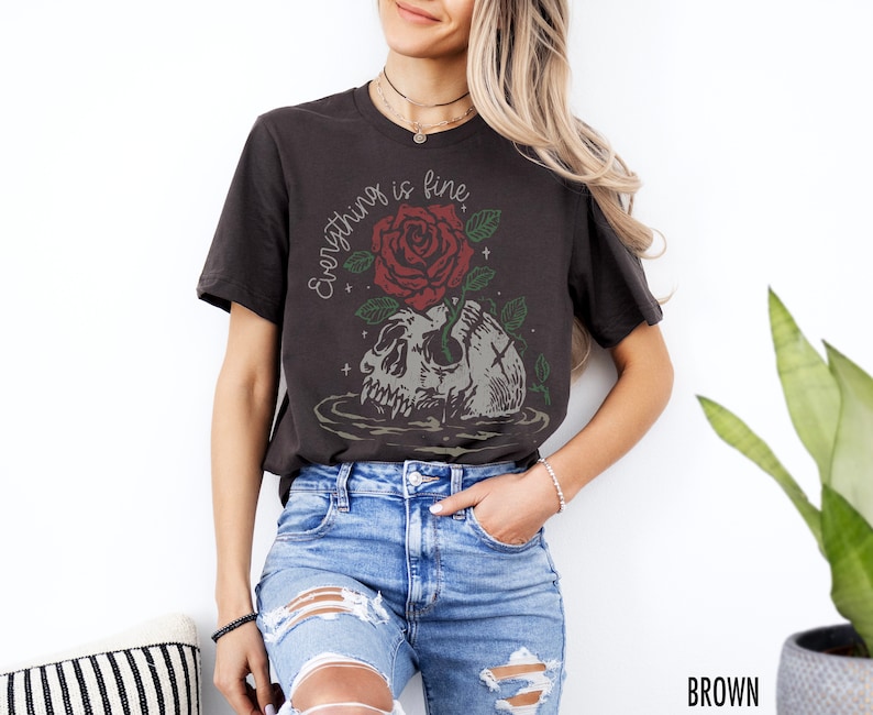 K&ouml;nnte beinhalten: Ein schwarzes T-Shirt mit einem Aufdruck eines Sch&auml;dels, aus dem eine rote Rose w&auml;chst. Der Text "Everything is fine" steht &uuml;ber dem Sch&auml;del.