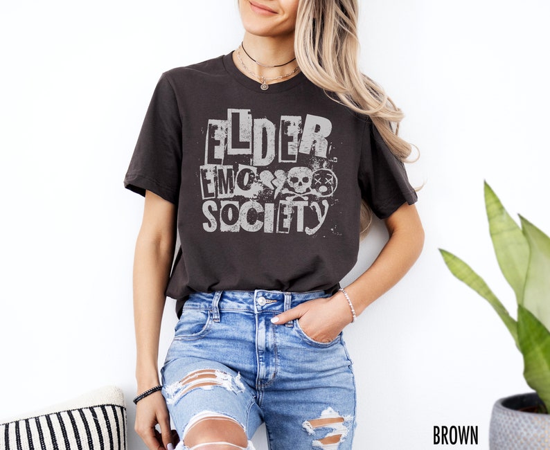 May include: A dark brown t-shirt with a white graphic print that says "FLDER EMO SOCIETY" with skull and crossbones.
