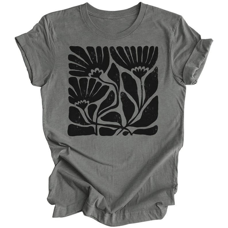 May include: A gray t-shirt with a black floral print. The print features stylized flowers and leaves in a blocky design.