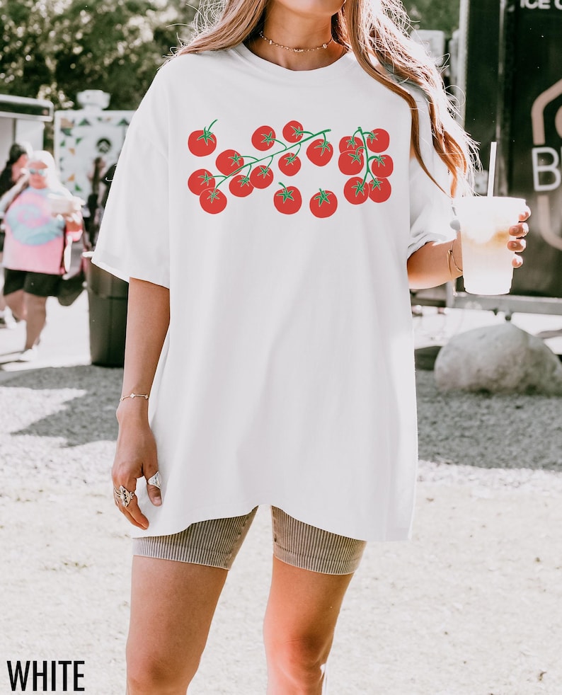 May include: White oversized t-shirt with a graphic of red tomatoes on a vine. The shirt is made of a soft, comfortable material.