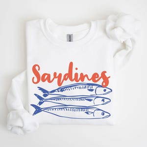 May include: White sweatshirt with the word "Sardines" in orange text and a blue illustration of three sardines.