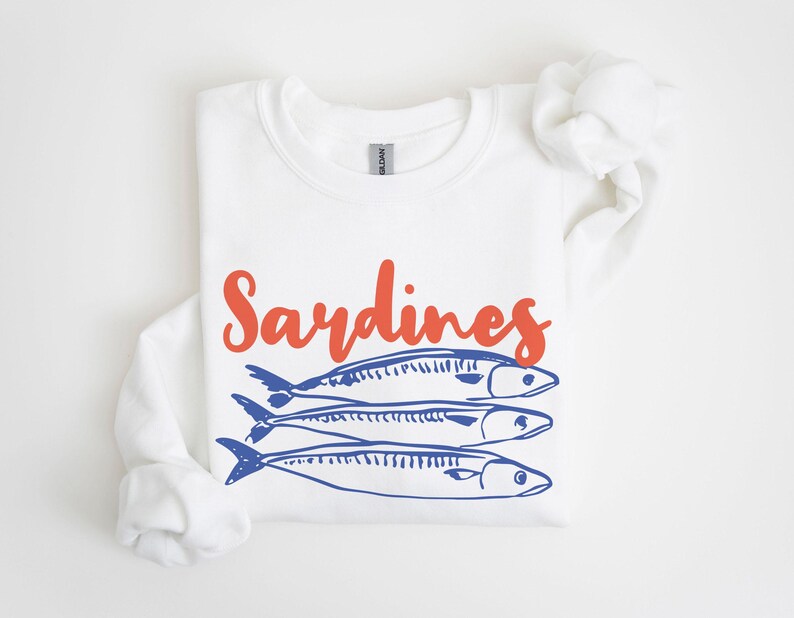 May include: White sweatshirt with the word "Sardines" in orange text and a blue illustration of three sardines.