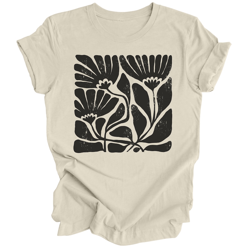 May include: A beige t-shirt with a black floral print. The print features stylized flowers and leaves in a block pattern.
