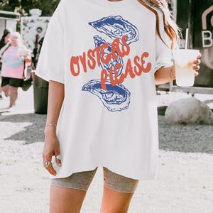 May include: White oversized t-shirt with a graphic of blue oysters and the text "Oysters Please" in red.
