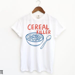 May include: White t-shirt with blue and red text that says "Cereal Killer". The shirt features a blue illustration of a bowl of cereal.