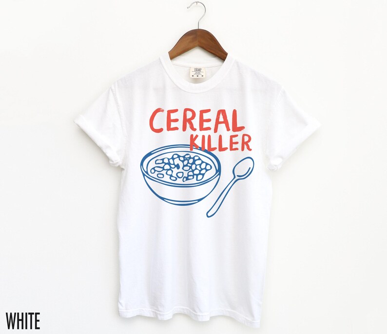 May include: White t-shirt with blue and red text that says "Cereal Killer". The shirt features a blue illustration of a bowl of cereal.