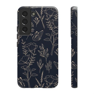 Puede incluir: Una funda de tel&eacute;fono negra con un patr&oacute;n floral en dorado. La funda tiene un recorte para la lente de la c&aacute;mara.