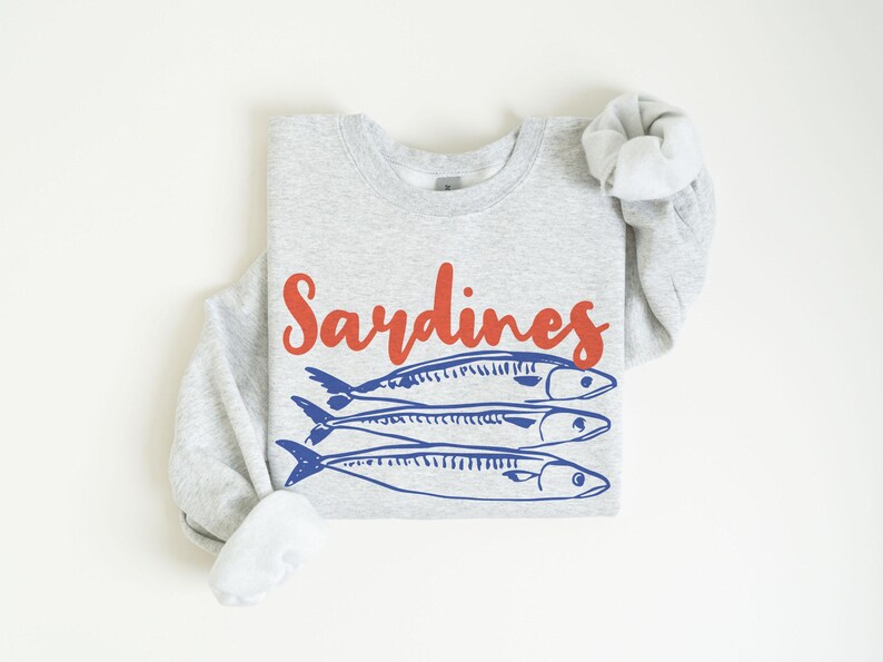 May include: A gray sweatshirt with the word "Sardines" printed in red and a graphic of three blue sardines.