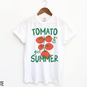 May include: White t-shirt with a green and red tomato graphic and the text "Tomato girl summer Italy".