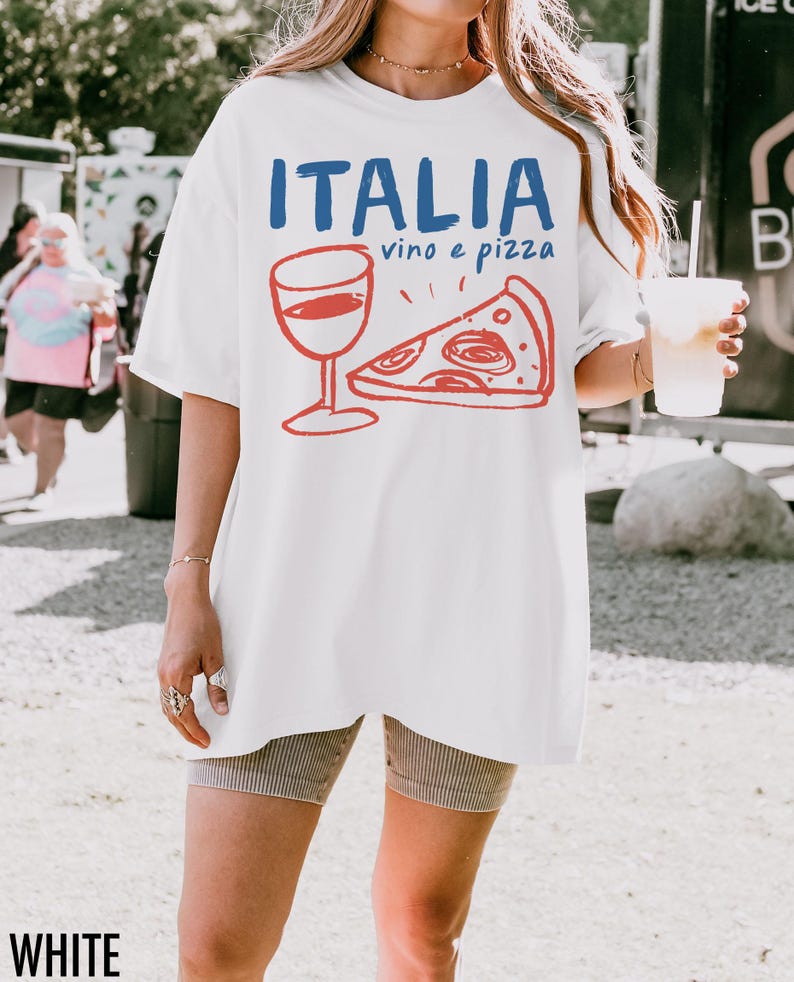 K&ouml;nnte beinhalten: Wei&szlig;es Oversize-T-Shirt mit einem Aufdruck eines Weinglases und einem St&uuml;ck Pizza. Der Text "ITALIA vino e pizza" ist auf das Shirt gedruckt.