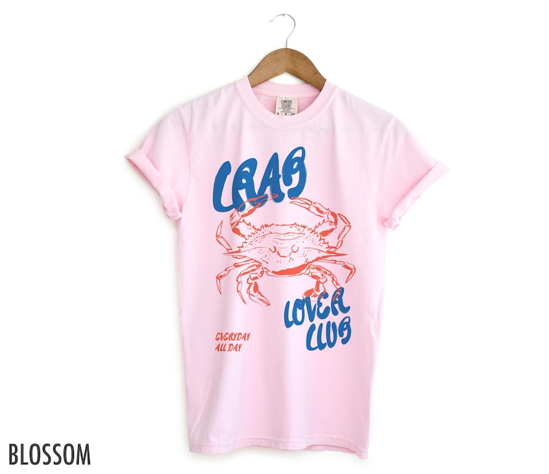 May include: Pink t-shirt with a blue and red graphic of a crab and the text "Crab Lover Club" and "Everyday All Day".