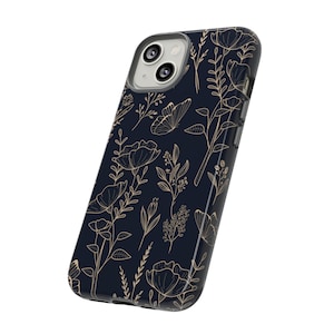 Puede incluir: Una funda de tel&eacute;fono negra con un patr&oacute;n floral dorado. La funda tiene un recorte para el objetivo de la c&aacute;mara.
