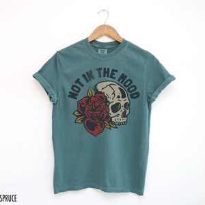 May include: Teal blue t-shirt with a skull and rose graphic and the text "Not in the Mood".