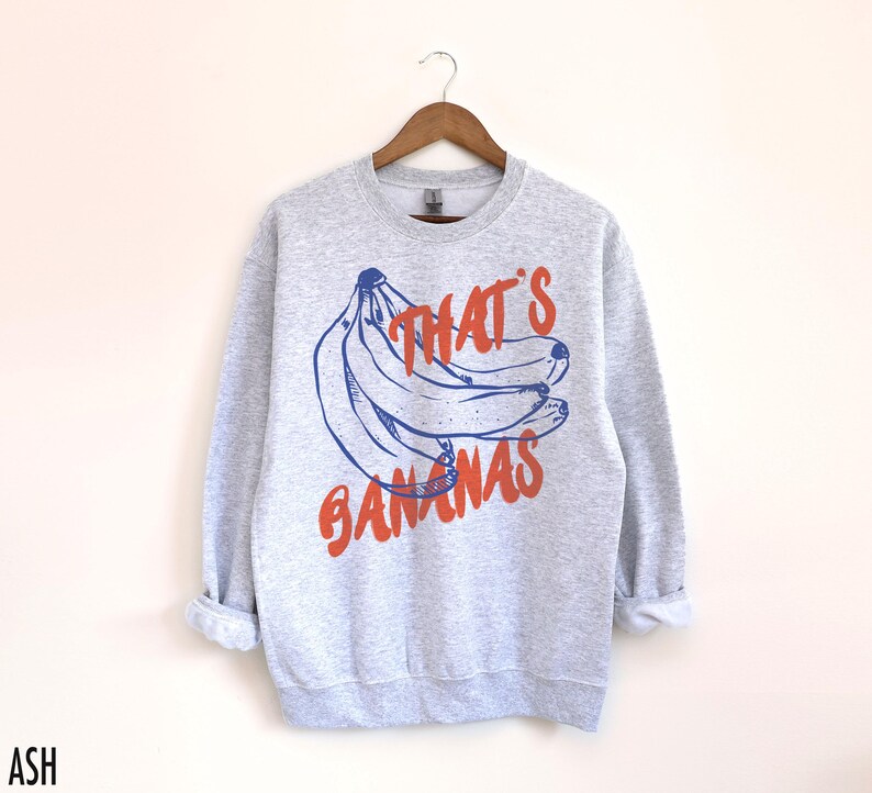 K&ouml;nnte beinhalten: Ein graues Sweatshirt mit einer blauen und orangenen Grafik von Bananen und dem Text "That's Bananas".