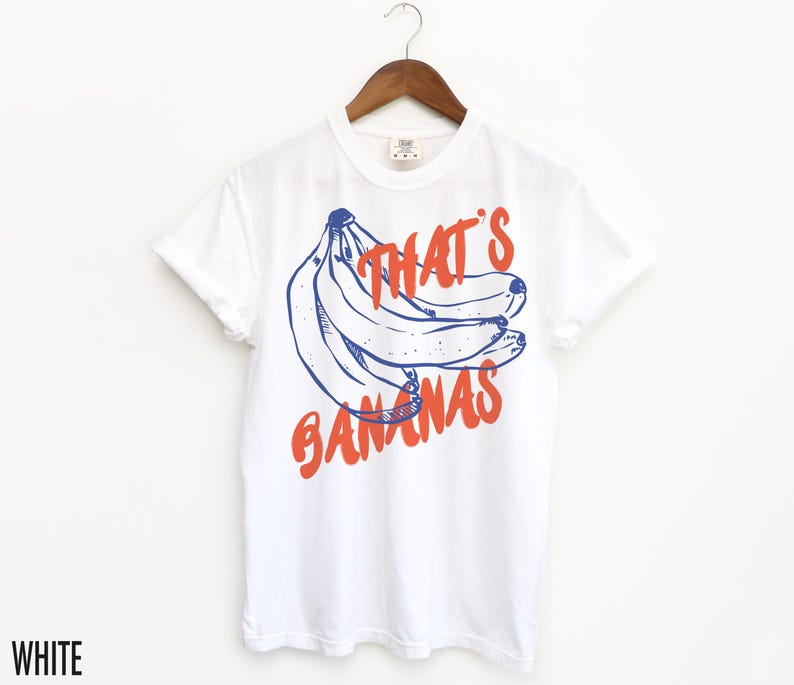 Pu&ograve; includere: Maglietta bianca con una grafica blu e arancione di banane e il testo "That's Bananas".