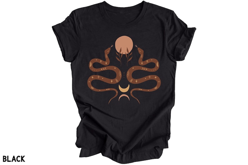 Puede incluir: Camiseta negra con un gr&aacute;fico de dos serpientes marrones entrelazadas alrededor de una luna amarilla y un sol de color melocot&oacute;n. Las serpientes tienen detalles dorados.