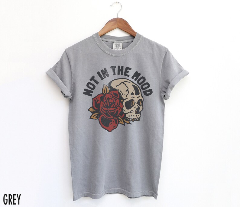 May include: Grey t-shirt with a skull and rose graphic and the text "Not in the Mood".