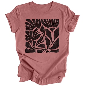 May include: A mauve t-shirt with a black floral print. The print features stylized flowers and leaves in a square shape.