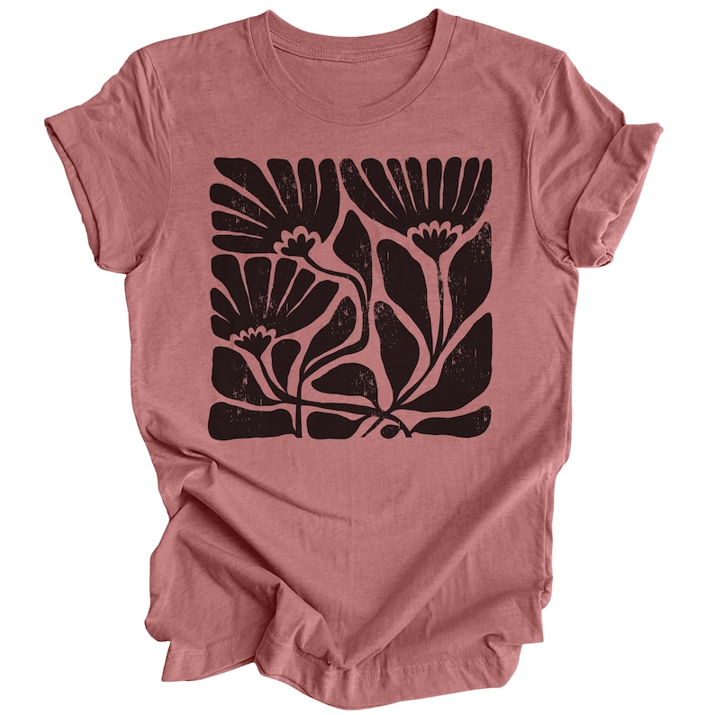 May include: A mauve t-shirt with a black floral print. The print features stylized flowers and leaves in a square shape.
