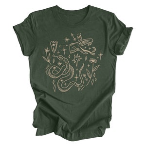 Puede incluir: Una camiseta verde oscuro con un estampado gr&aacute;fico beige de una serpiente, estrellas y otros s&iacute;mbolos m&iacute;sticos.