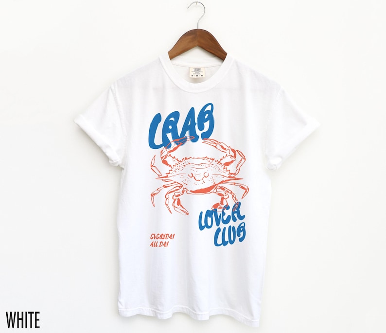 May include: White t-shirt with a blue and red graphic of a crab with the text "Crab Lover Club" and "Everyday All Day" printed on the front.