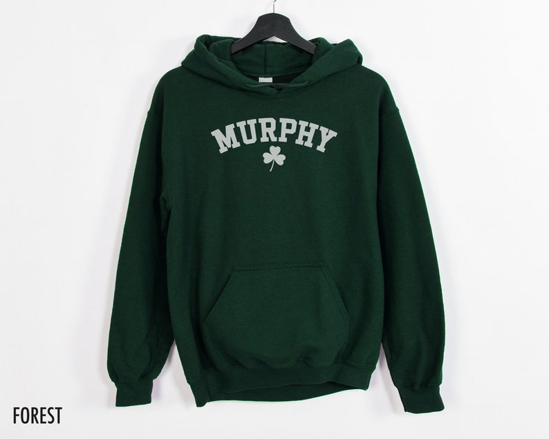 May include: A dark green hooded sweatshirt with the word "MURPHY" in white letters and a silver shamrock underneath. The sweatshirt has a kangaroo pocket.
