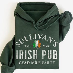 May include: Dark green hoodie with the text "SULLIVAN'S IRISH PUB" in white, along with a shamrock in the colors of the Irish flag. The hoodie has a drawstring and a kangaroo pocket. The text "CÉAD MÍLE FÁILTE" is printed at the bottom.