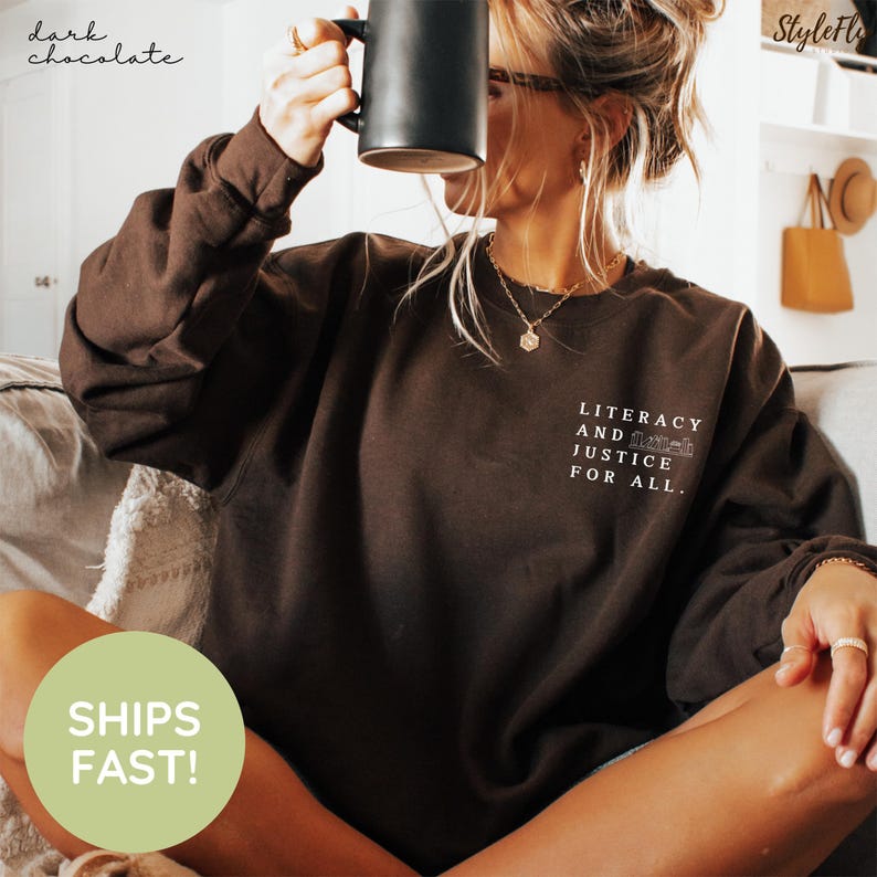Puede incluir: Sudadera de color chocolate oscuro con el texto blanco "Literacy and Justice for All". La sudadera tiene mangas largas y cuello redondo. Las palabras "dark chocolate" est&aacute;n escritas en cursiva en la esquina superior izquierda.