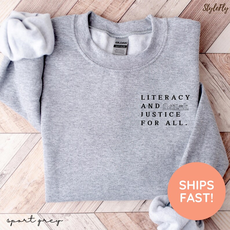 Puede incluir: Sudadera gris deportiva con el texto "LITERACY AND JUSTICE FOR ALL" en negro. La sudadera tiene cuello redondo y mangas largas. Tambi&eacute;n son visibles las palabras "StyleFly" y "sport grey".