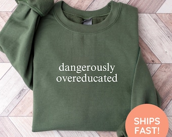 May include: Military green sweatshirt with the text "dangerously overeducated" in white. The sweatshirt has a crew neck and long sleeves. The words "military green" are written in cursive at the bottom.