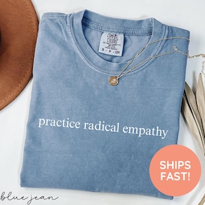 May include: A light blue t-shirt with the text "practice radical empathy" printed in white on the front.