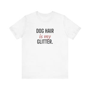 Könnte beinhalten: Weißes T-Shirt mit dem Text "DOG HAIR is my GLITTER" in Schwarz und Rot. Das T-Shirt mit Rundhalsausschnitt ist aus weichem Material. Der Text ist mittig auf der Vorderseite des T-Shirts platziert.