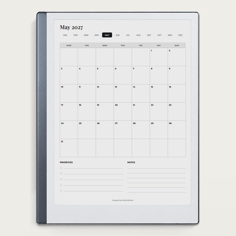 May include: A digital tablet displaying a May 2027 monthly calendar page. The screen features a grid layout with days of the week, numbered dates, and sections for priorities and notes at the bottom. The device has a dark gray frame.