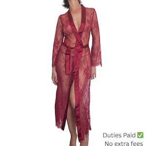 Może przedstawiać: Bordowa koronkowa szata z długimi rękawami i satynowym paskiem. Szata ma dekolt w kształcie litery V i długi krój. Na zdjęciu kobieta ma na sobie szatę.