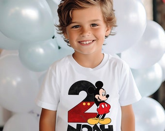 May include: A white short-sleeved t-shirt featuring a large red number two with a black outline, a graphic of Mickey Mouse standing in front of the number, and the name NOAH printed in bold black capital letters below the graphic.