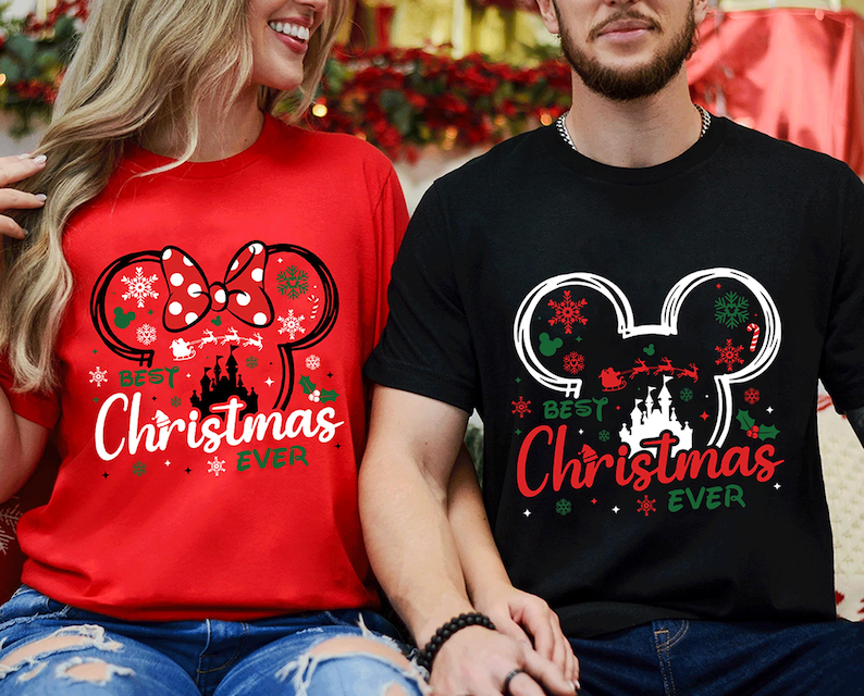 May include: A red t-shirt and a black t-shirt, each featuring a graphic of a mouse ear silhouette filled with snowflakes, a castle, and a Santa sleigh. The text "BEST Christmas EVER" is printed in white and red lettering on the shirts.