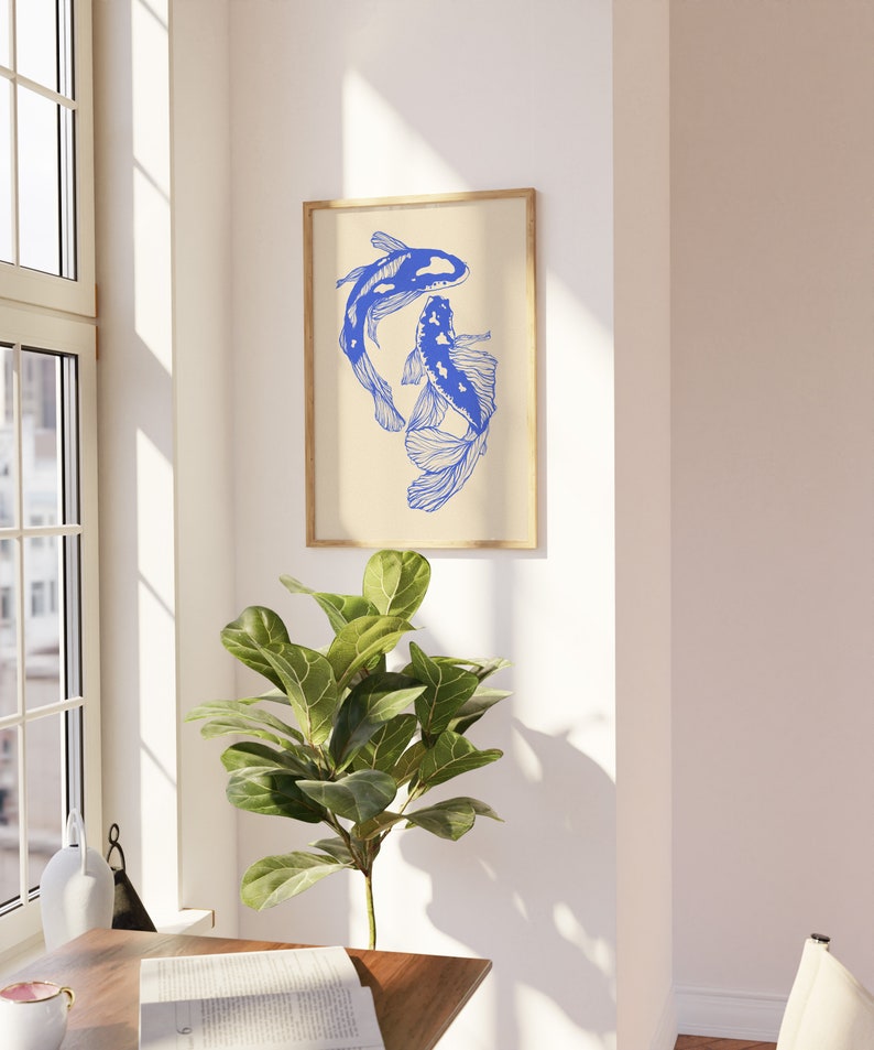 Pode incluir: Uma impress&atilde;o emoldurada de dois peixes koi azuis nadando em um design estilizado sobre um fundo creme. A impress&atilde;o est&aacute; pendurada em uma parede branca.