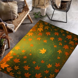 May include: A rectangular rug with a green and yellow gradient background, adorned with orange maple leaves. The design features a central leaf with concentric circles, creating a water ripple effect. The rug is suitable for indoor use.