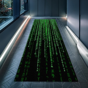 Peut inclure: Un tapis noir et vert avec un motif répété de code vert sur fond noir. Le tapis est posé sur un sol en carrelage gris.