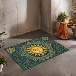 Könnte beinhalten: Rechteckiger, türkisfarbener Teppich mit einem goldenen Sonnendesign in der Mitte, das ein ruhiges Gesicht zeigt. Die Sonne ist von einem verzierten, floralen Rand umgeben. Zusätzliche florale Medaillons schmücken die Ecken.